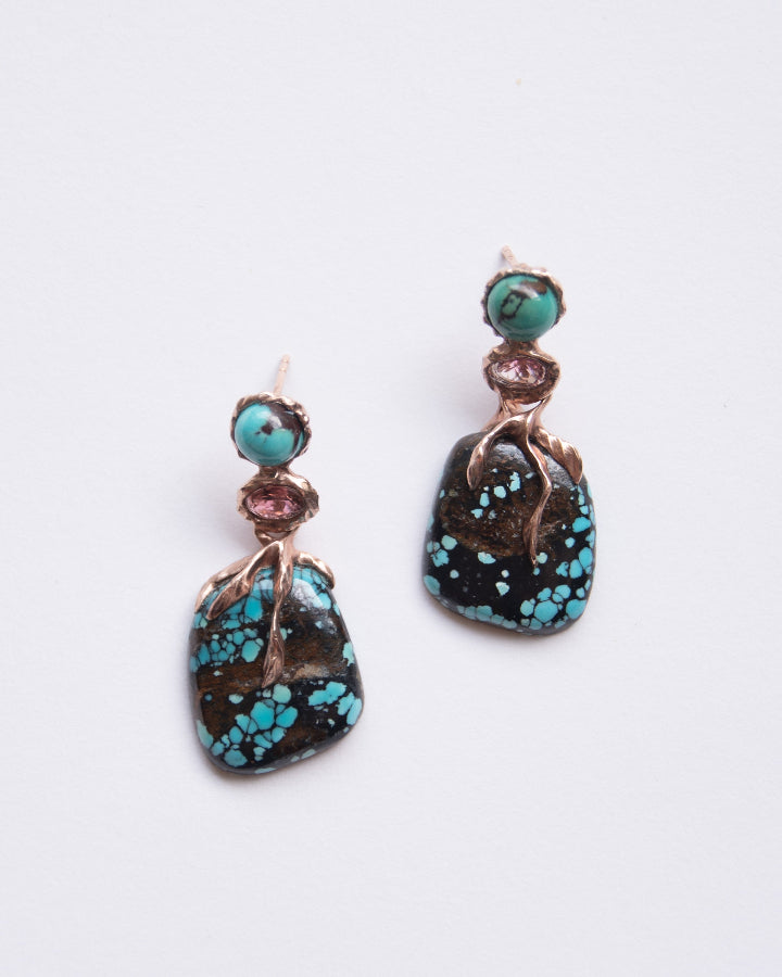 front view of earrings featuring spider-web turquoise and pink tourmaline set in a molten sculpted rose gold-plated silver setting