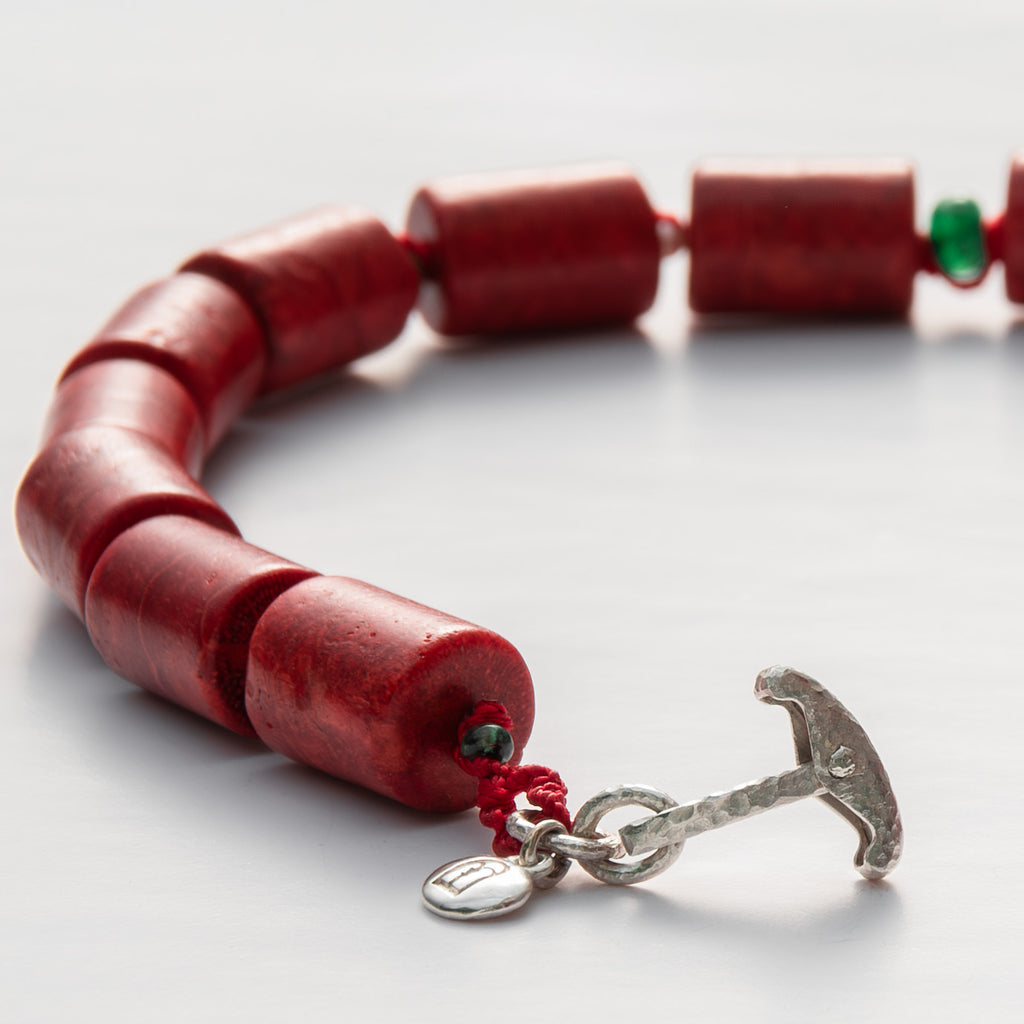 Red beaded bracelet with a silver anchor clasp on a white background