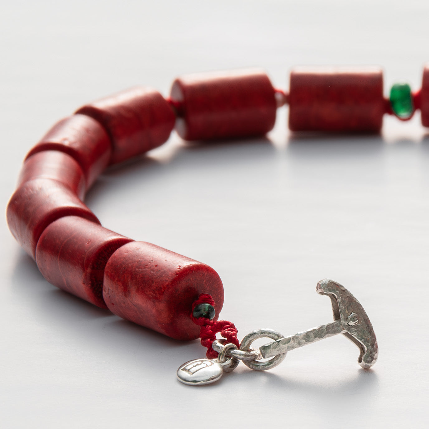 Red beaded bracelet with a silver anchor clasp on a white background