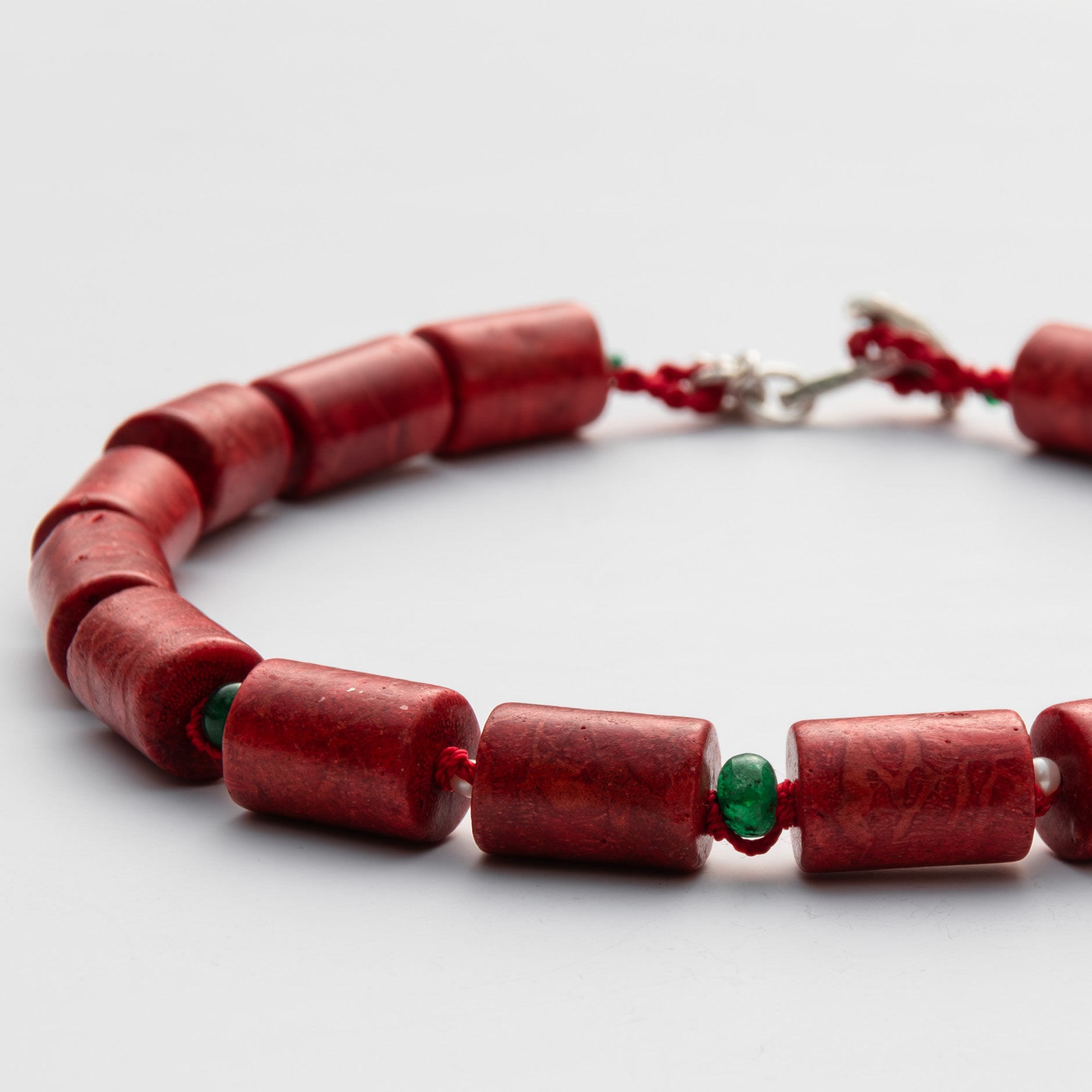 Red beaded necklace with a silver clasp on a light gray background