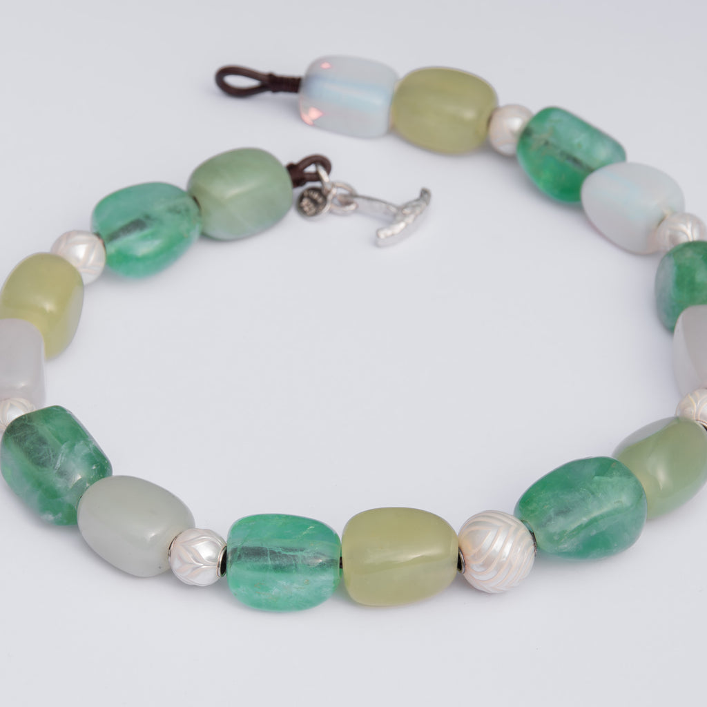 Beaded necklace with green, white, and pearl beads on a white background