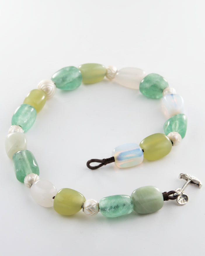 Beaded necklace with green and white beads on a white background
