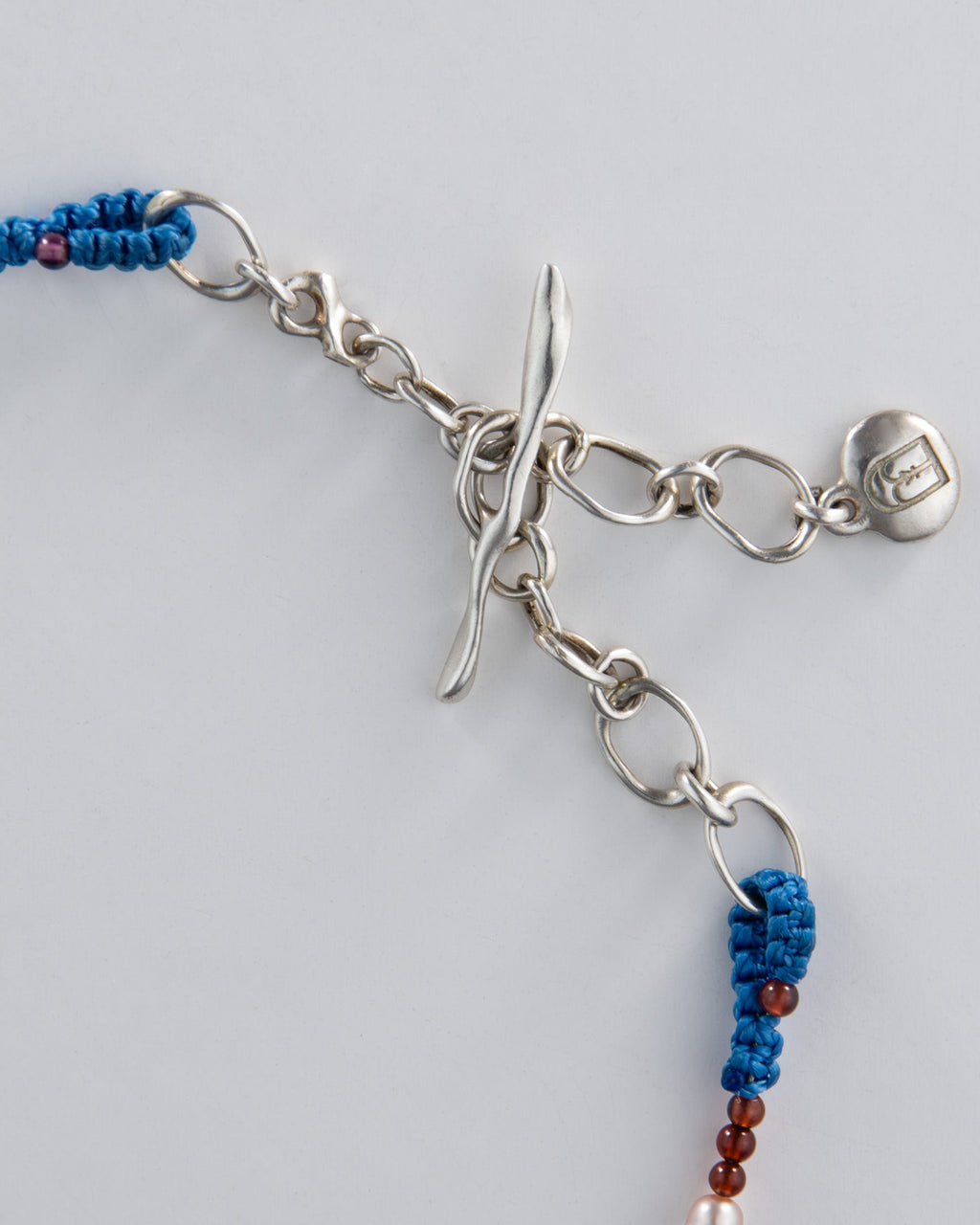 Silver necklace with blue and red beads on a light grey background