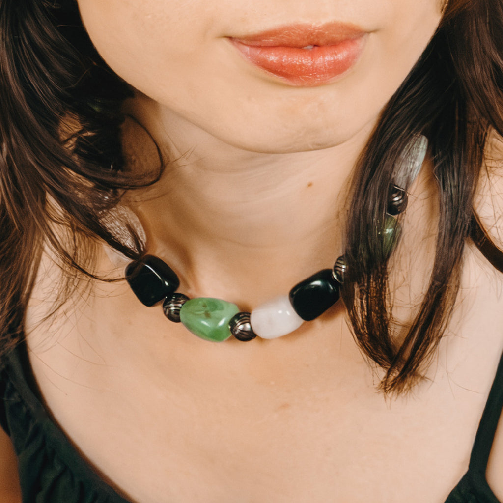 Close-up of a person wearing a necklace with black, green, and white beads.