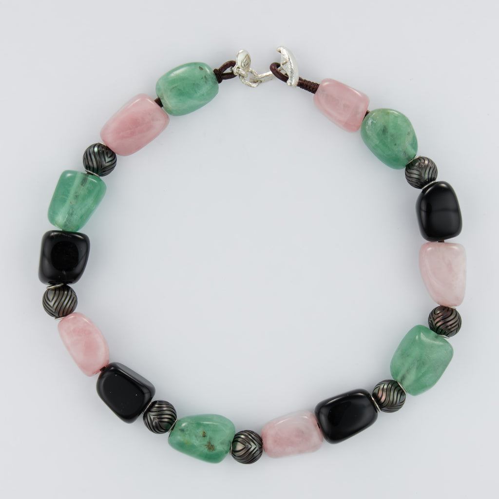 Beaded bracelet with green, pink, and black beads on a white background