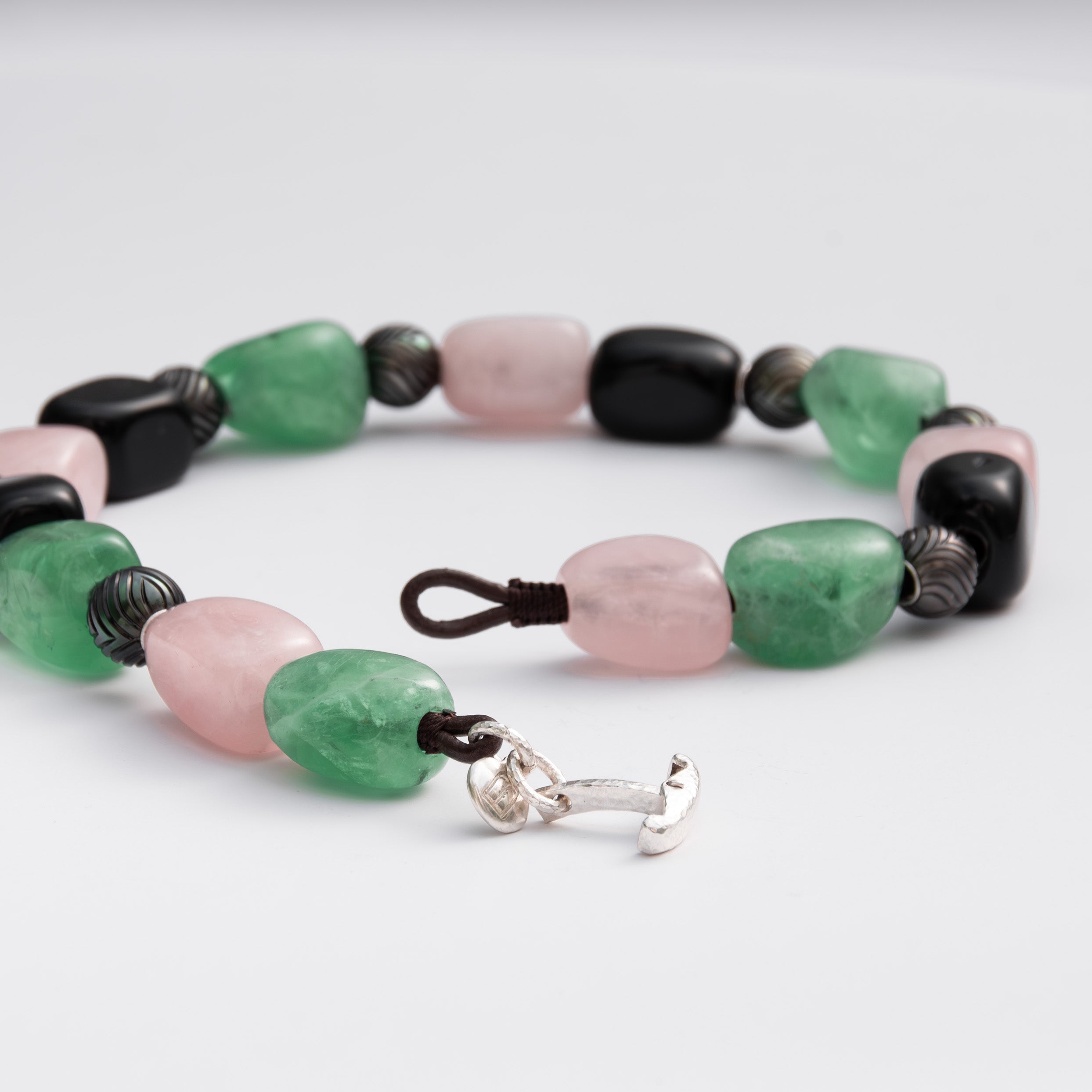 Necklace with green, pink, and black beads on a white background