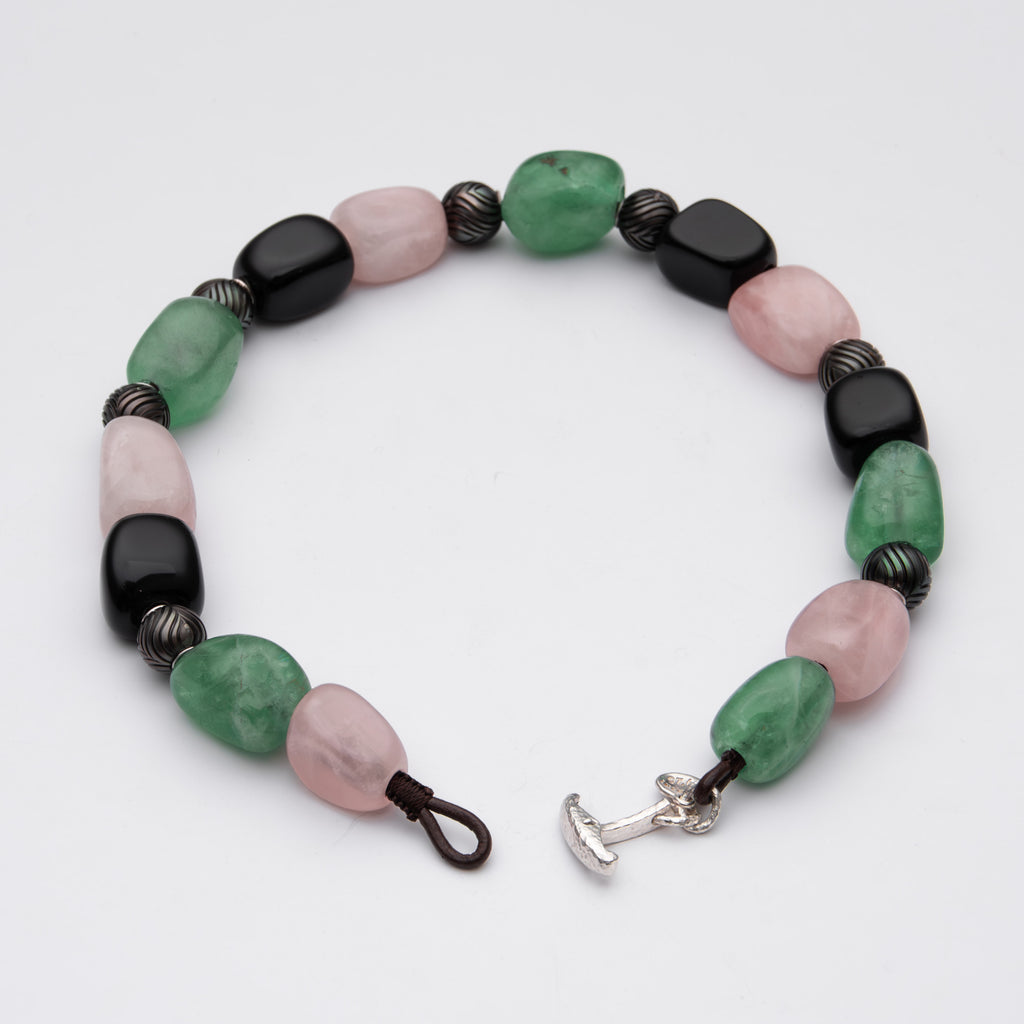 Necklace with green, pink, and black beads on a white background
