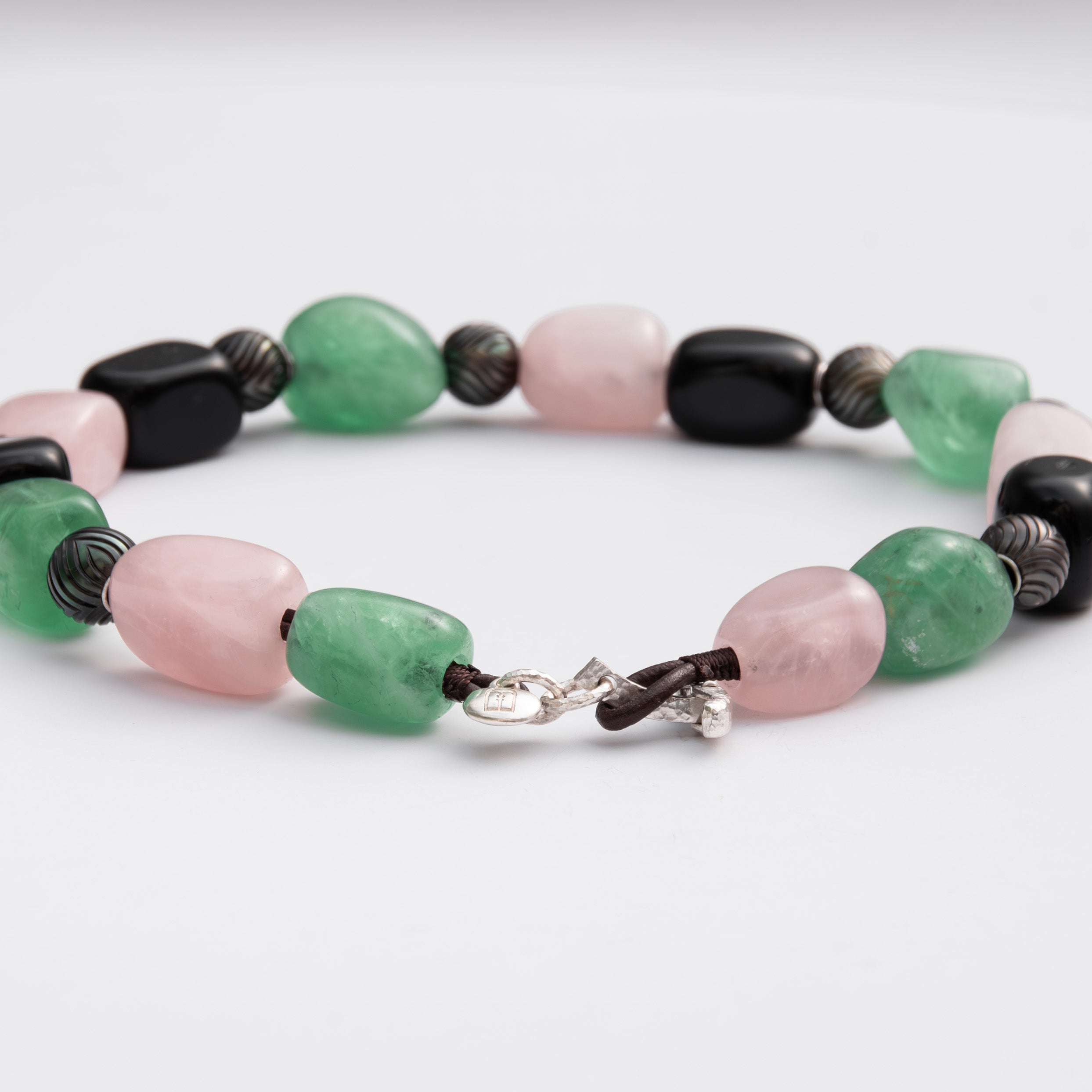Necklace with green, pink, and black beads on a white background