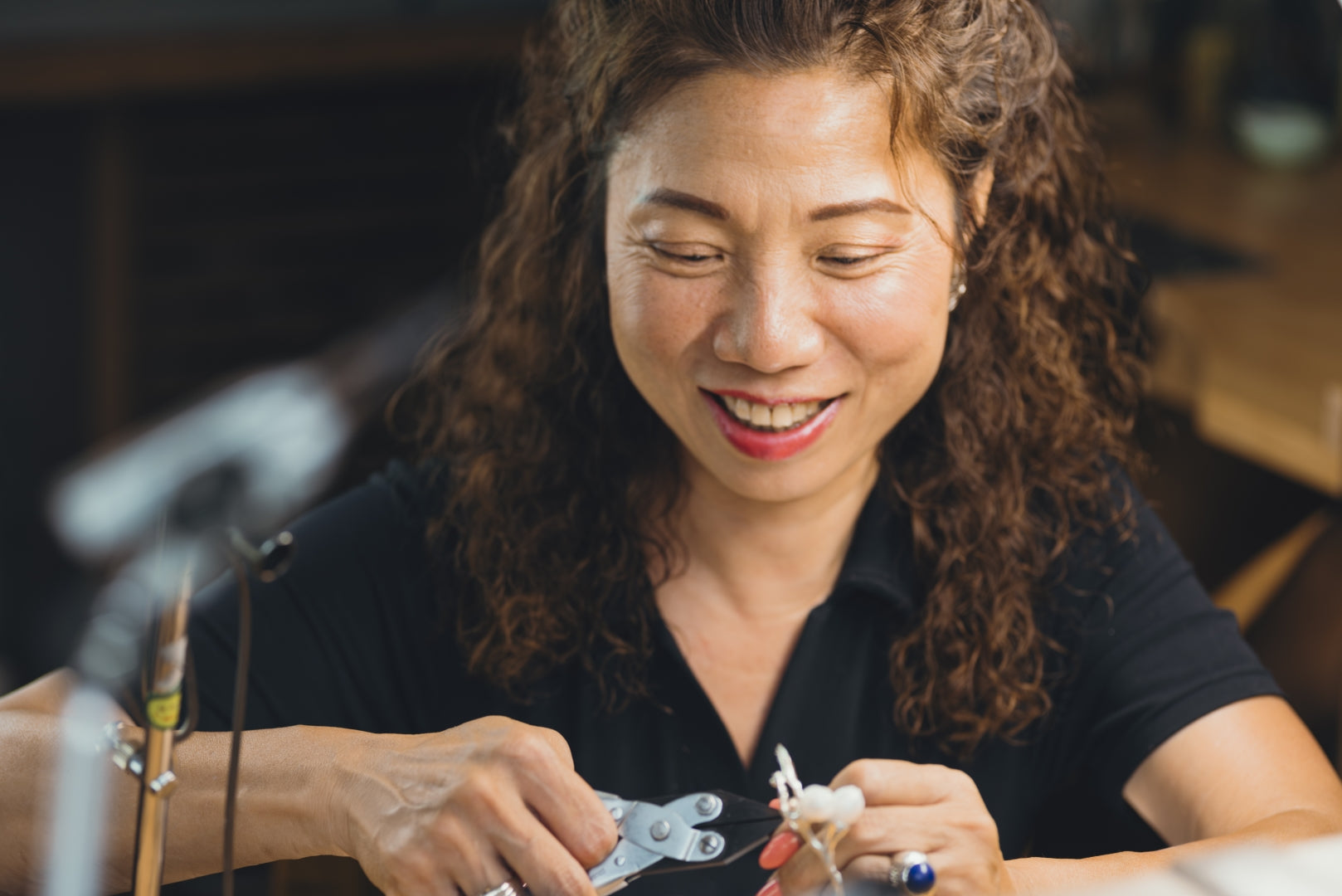 Woman working on a small object with tools in a workshop setting
