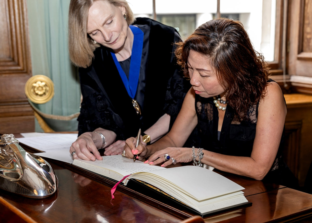Annie Warburton, Chief Executive and Clerk of The Goldsmiths’ Company  beside Bibi signing her declaration in Freedom Ceremony at Goldsmiths' Hall
