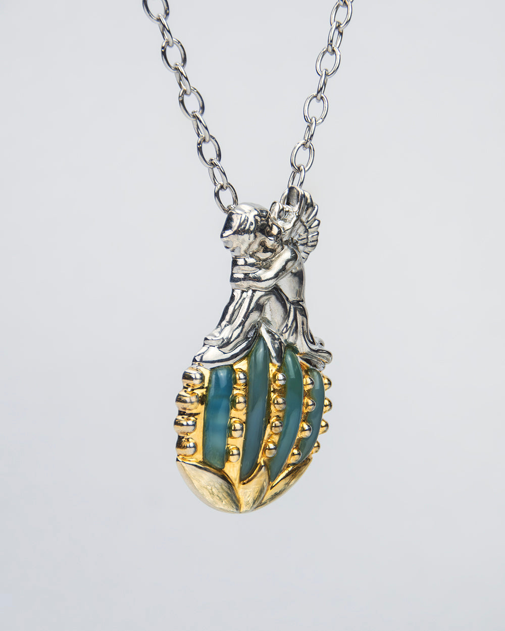 angled view of a pendant depicting a cherub sitting on a sphere, highlighting its finely sculpted details
