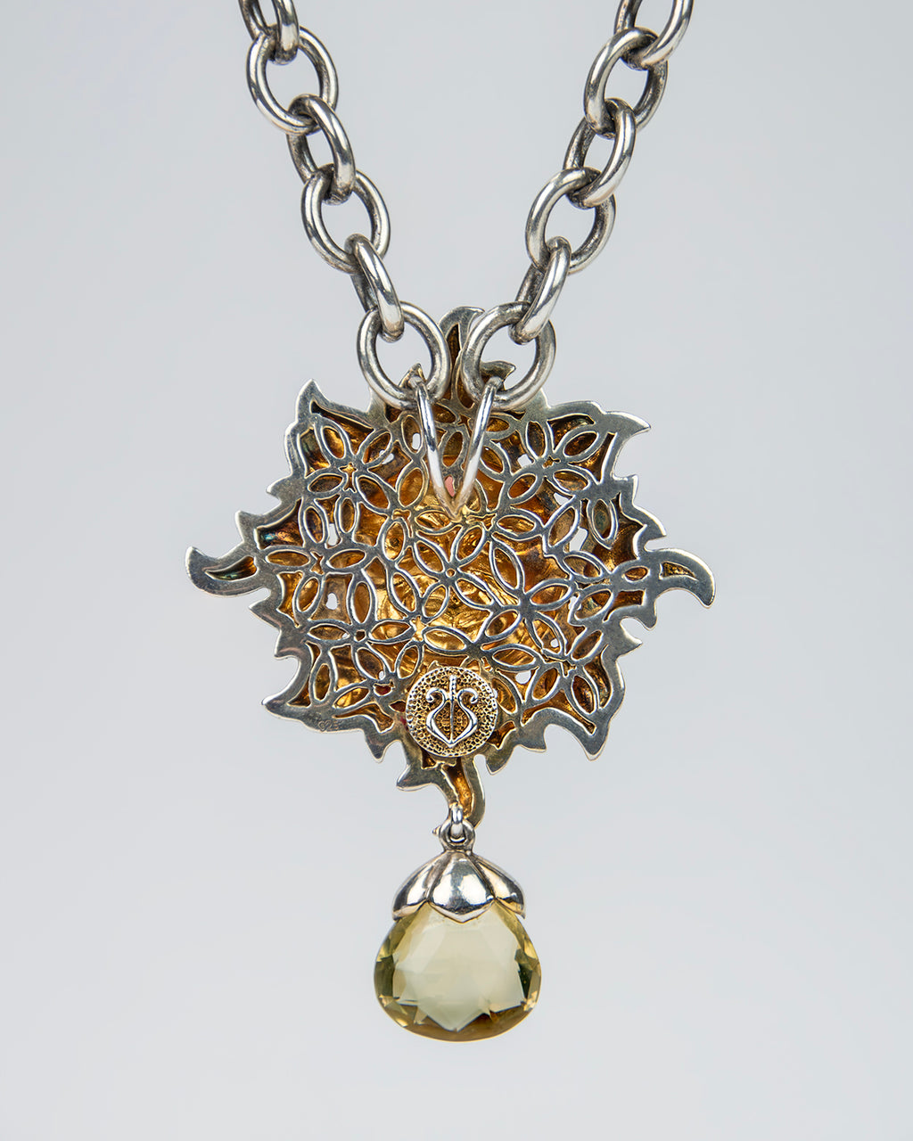 close-up of a silver pendant necklace, exhibiting the fine detailing behind the main face and high polish