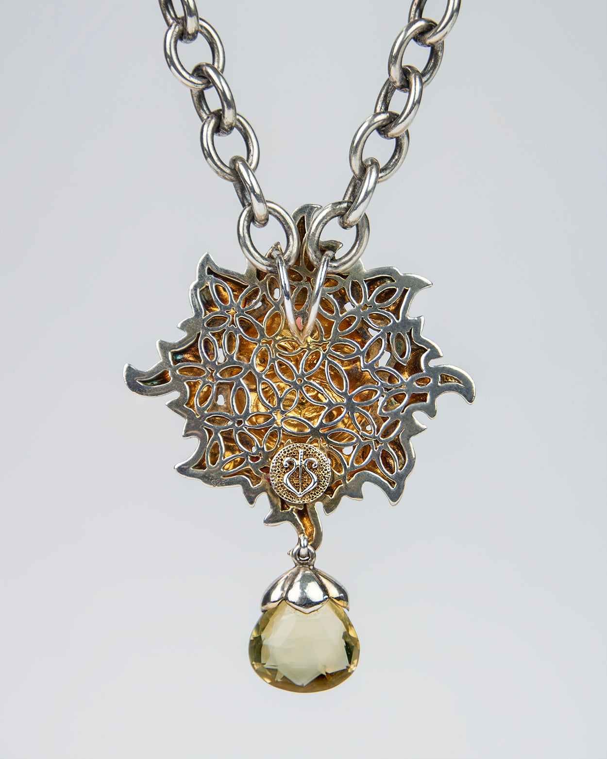 close-up of a silver pendant necklace, exhibiting the fine detailing behind the main face and high polish