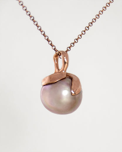 angled view of a pearl pendant, showcasing free-form setting crafted from gold-plated silver