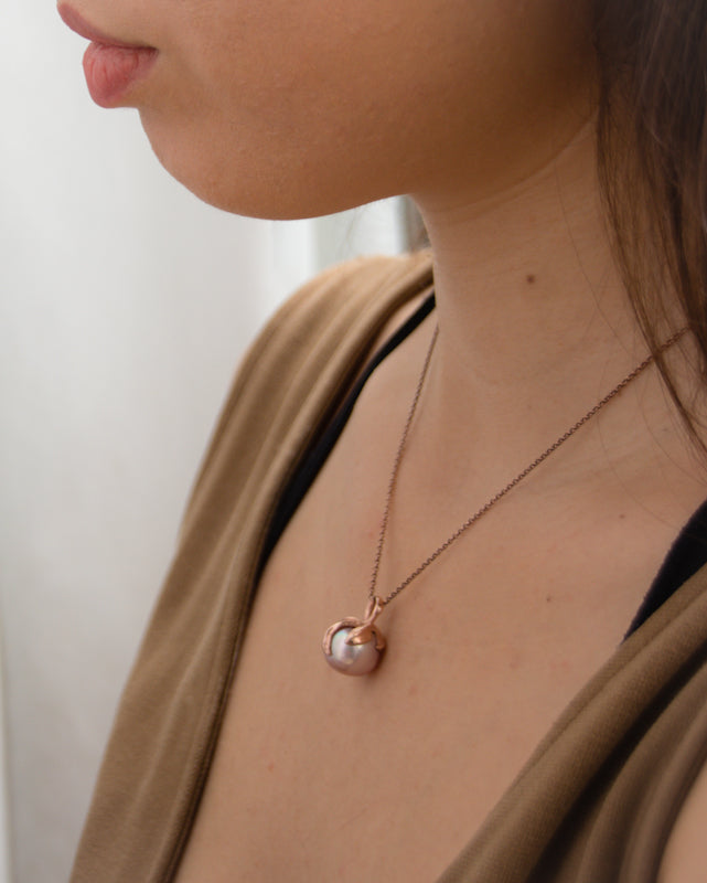 model wearing a gold-plated silver pendant, showcasing its sculptural, free-form design