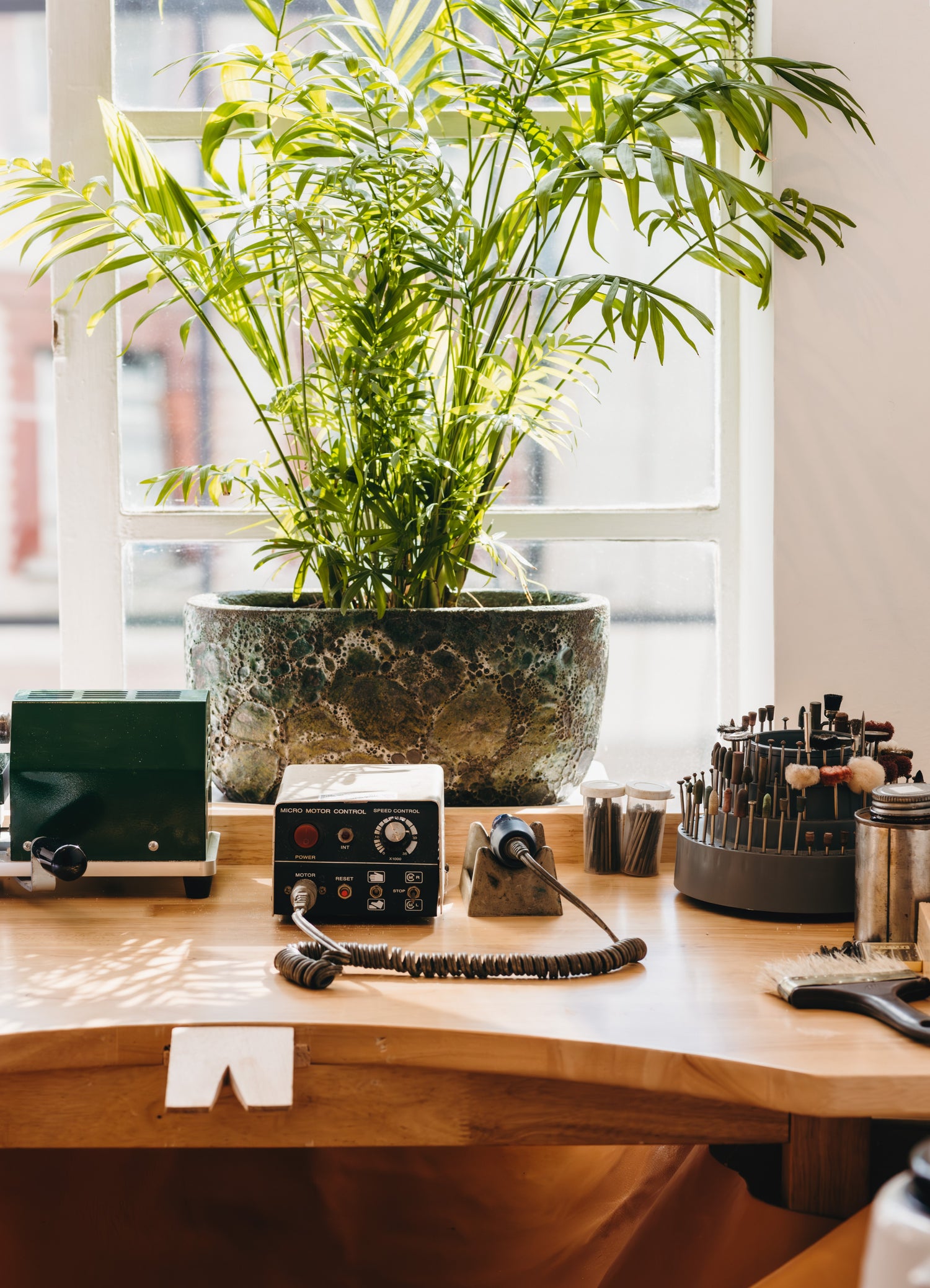 Jeweller's bench with assorted tools and plant facing an office building