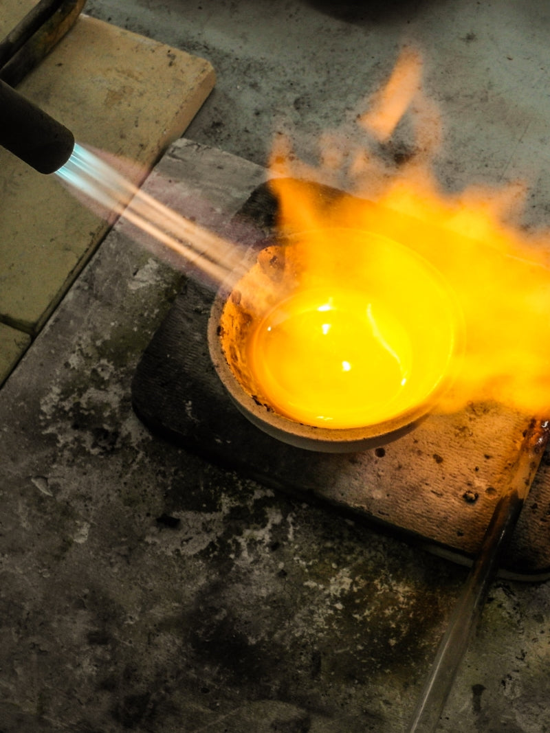 A gas torch melting metal in a crucible