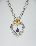 front side of a silver pendant, featuring a briolette-cut amethyst hanging in the middle of a heart with a flame at the top plated with yellow gold