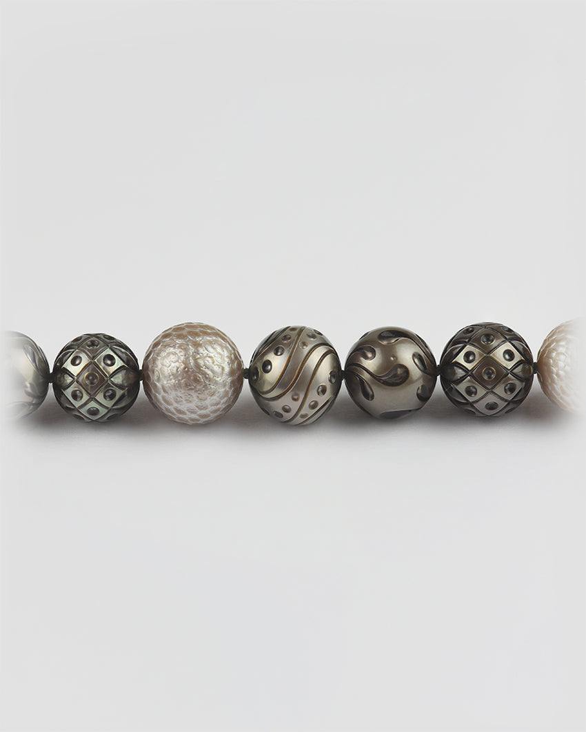 Dark and light Tahitian pearls with assorted hand-engraved patterns on a strand