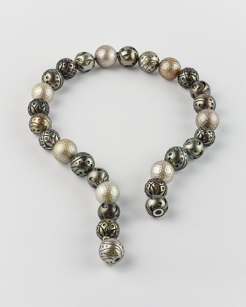 Strand of alternating dark and light Tahitian pearls with hand-engraved patterns arranged to reveal magnetic clasp