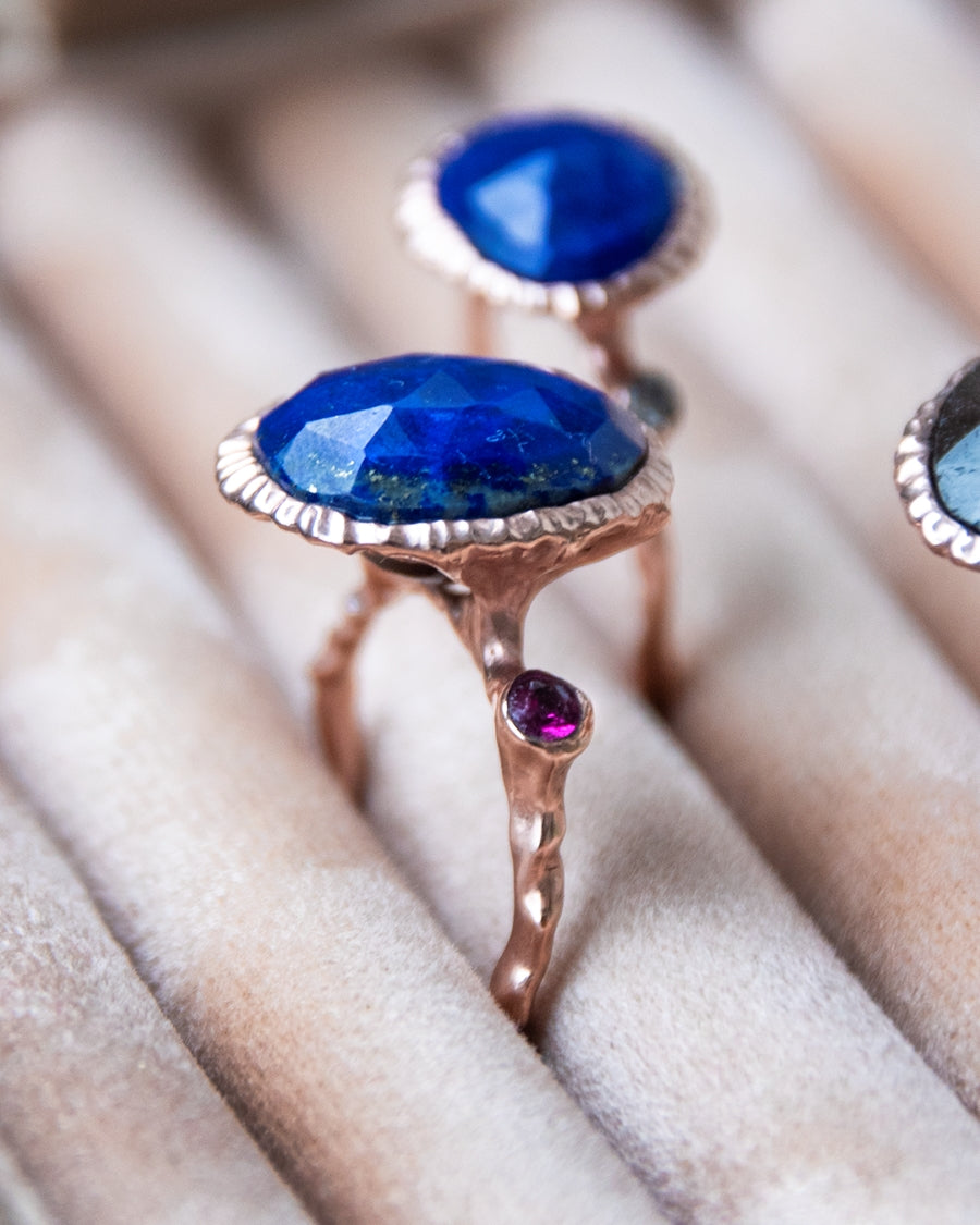 angled view of several rings, featuring central stones set in a modern, organic setting of gold-plated silver