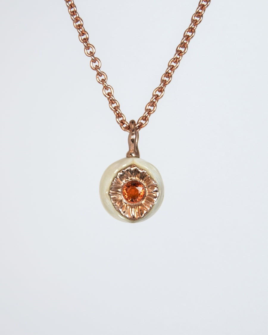 close-up of a rose gold-plated silver pendant with freshwater pearl and orange sapphire