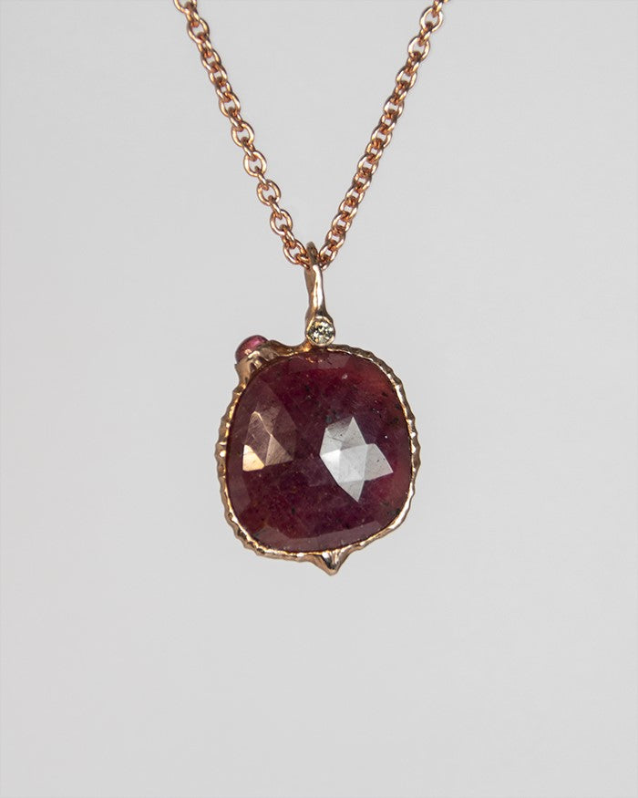 close-up of a pendant featuring a rose-gut garnet set in a free-form gold-plated silver setting, with pink tourmaline and diamond on the side