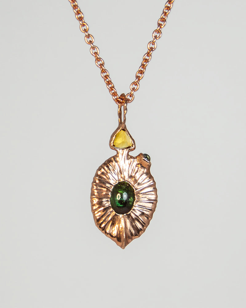 Rose gold-plated pendant necklace with central green oval gemstone and a small yellow accent at the top.