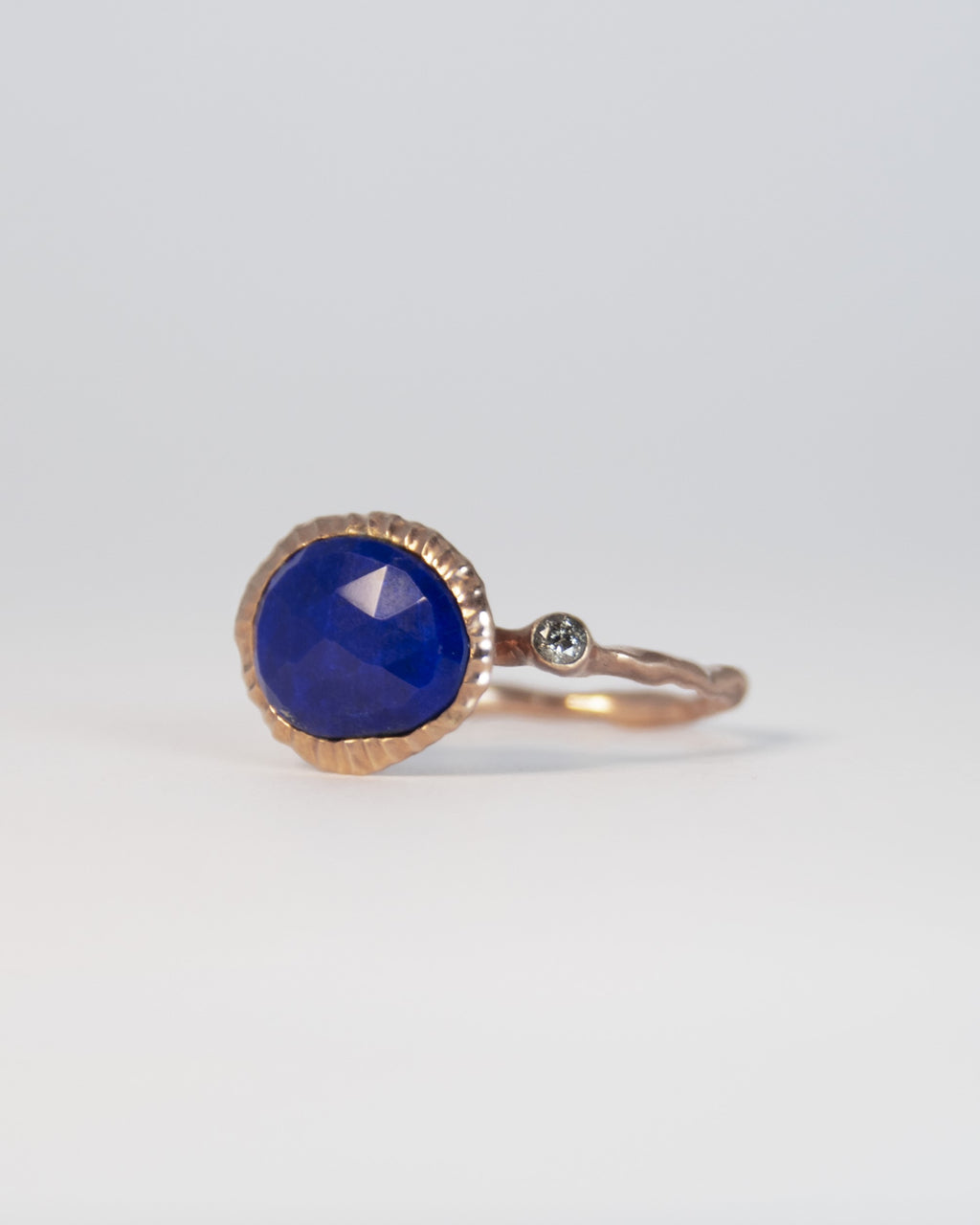 angled view of a gold-plated sterling silver ring, emphasising the deep blue lapis lazuli centrepiece and diamond side