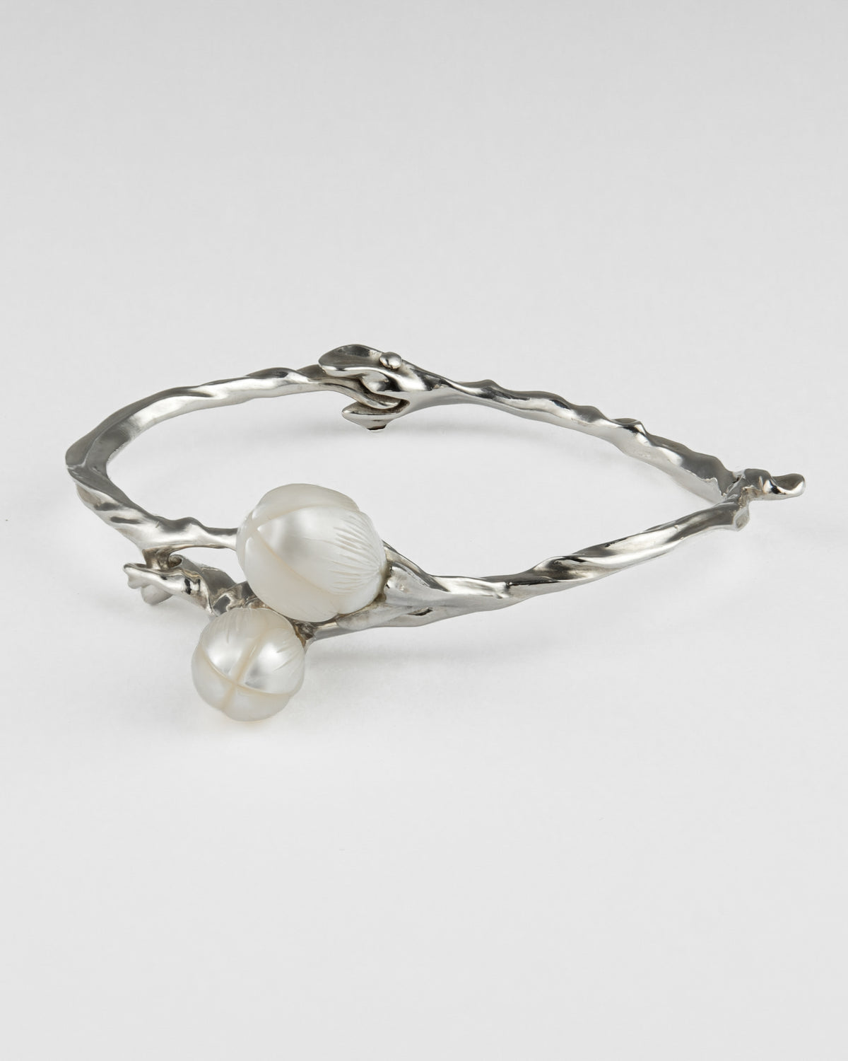A silver twisted branch-style bangle featuring two large white carved pearls.