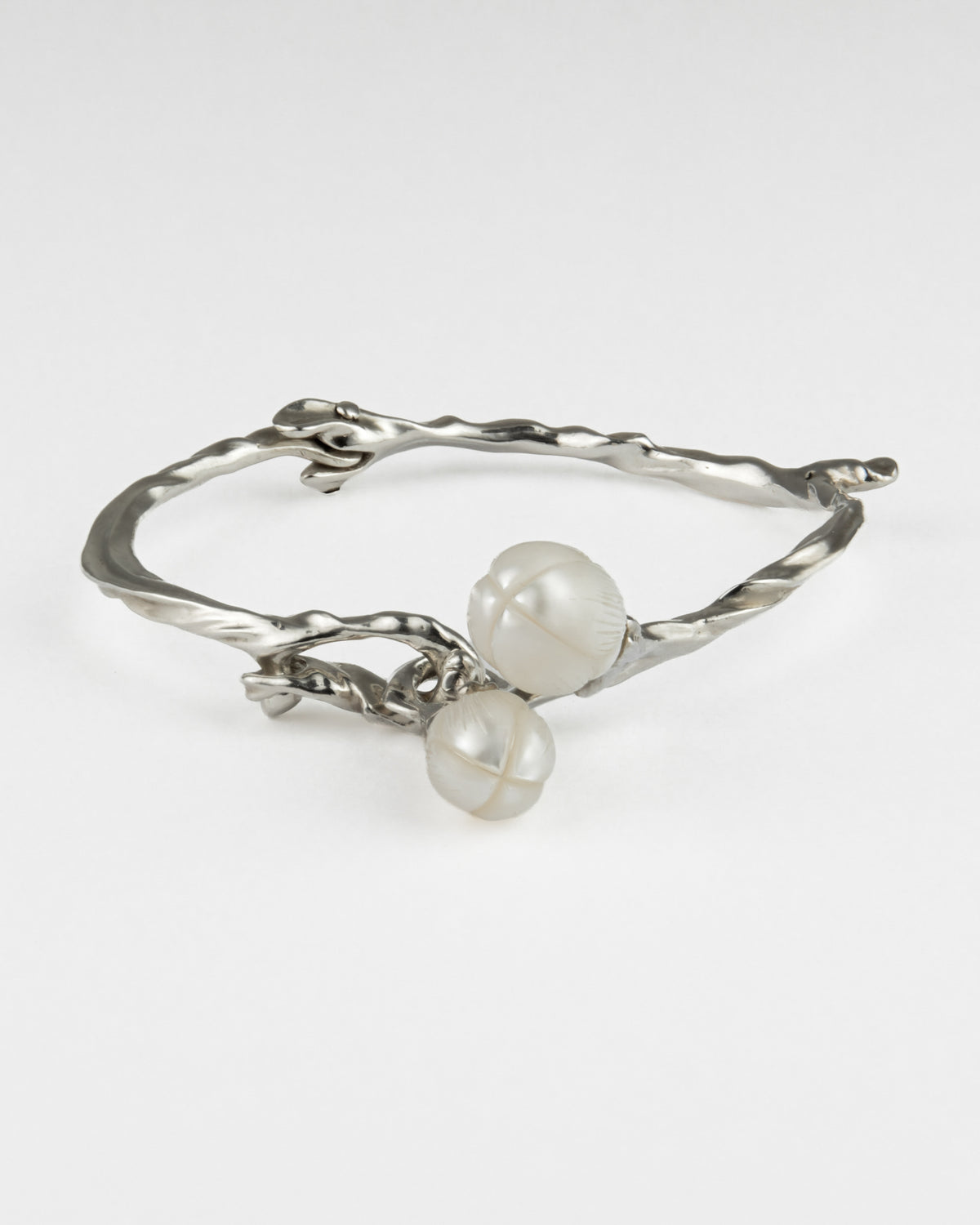 A silver twisted bracelet featuring two smooth, white pearls hanging from the front.