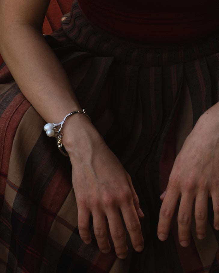 A close-up of a person's wrist wearing a silver bracelet with white pearl.
