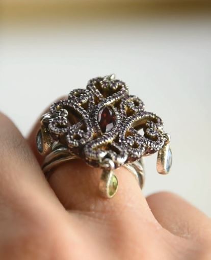 close-up of silver ring on hand, exhibiting gemstones hanging off the ring head