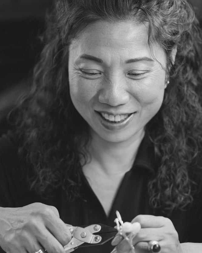 Woman working on a small object with tools in a workshop setting