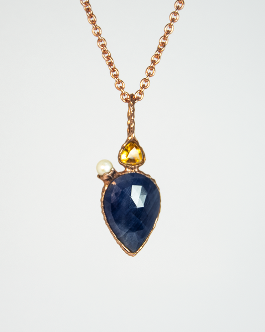 A front view of Nisi Vessel Pendant in 18K Rose Gold with Blue Sapphire, Citrine and Freshwater Pearl: reverse side includes Rubellite
