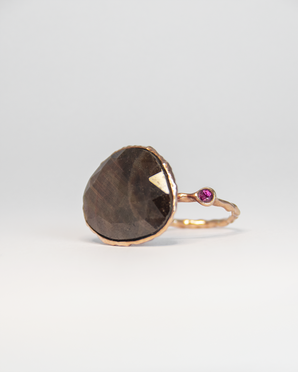 Angled view of Nisi Island Ring in 18K Rose Gold with Gold-Sheen Sapphire