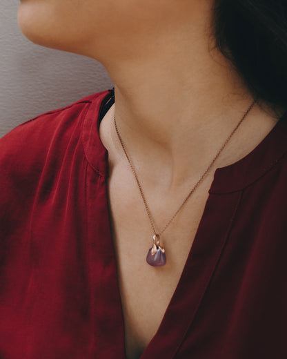 Close-up of a purple chalcedony pendant with a free-form silver design, worn by a model with natural outdoor lighting