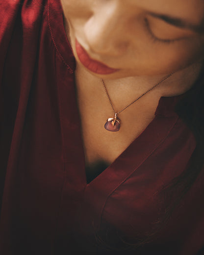 An angled view of a model wearing a purple chalcedony pendant with a free-form silver setting, highlighting its graceful design against her neckline