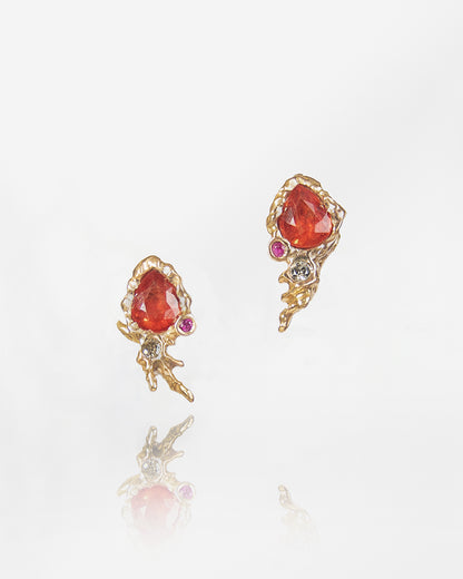 front view of earring studs featuring orange sapphires, rubies, and diamonds framed by 18K rose gold