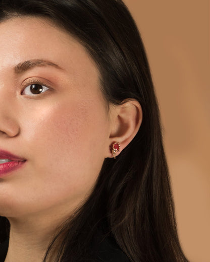 close-up of model wearing sculpted 18K rose gold stud earrings with orange sapphire, rubies and diamonds as part of a detachable set