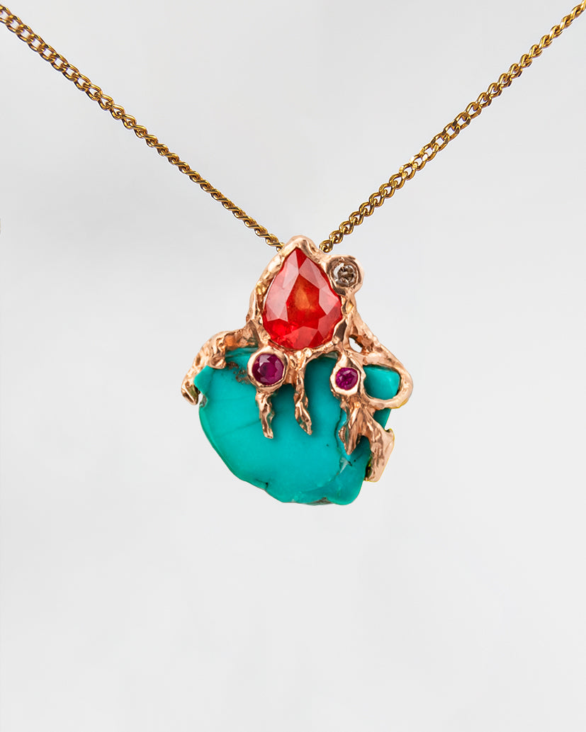 Front view of pendant with s free-form 18K gold setting, featuring turquoise, orange sapphire, ruby and diamond  