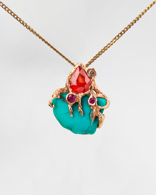 Front view of pendant with s free-form 18K gold setting, featuring turquoise, orange sapphire, ruby and diamond  