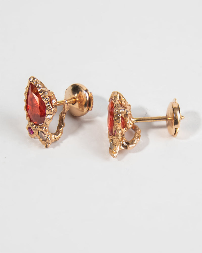 angled view of 18K rose gold studs with alpha backs, highlighting abstract, molten design encasing each gemstone