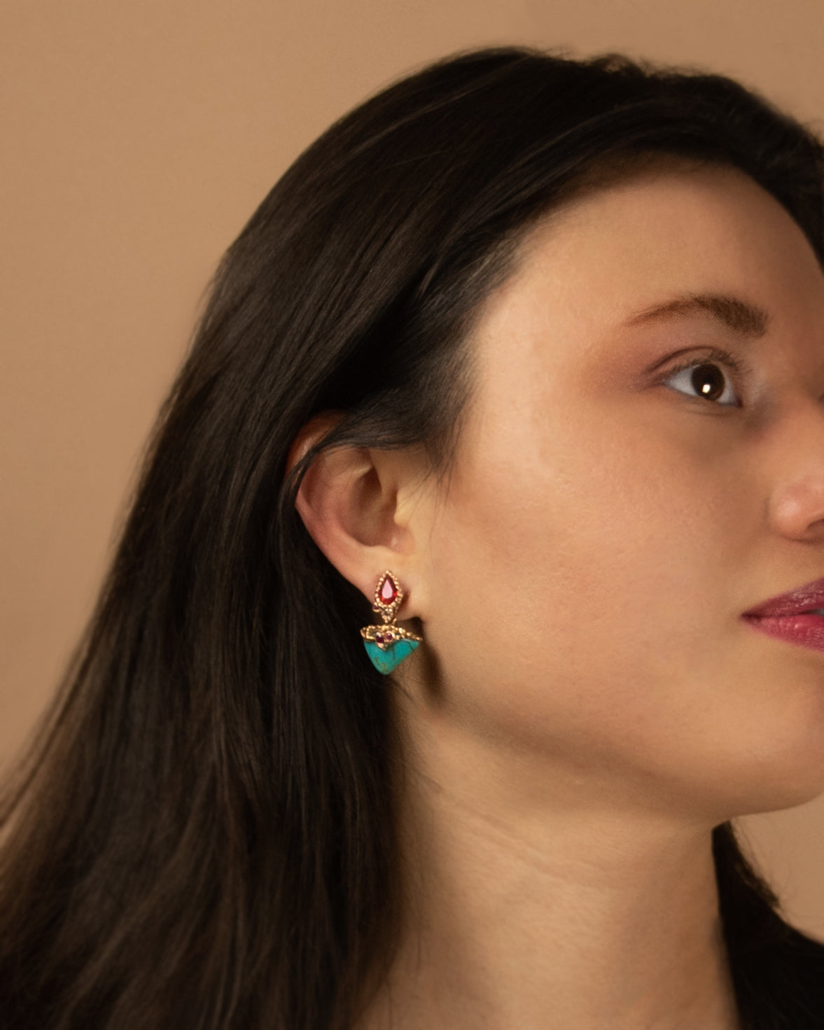 a model wearing a set of Lava earrings, featuring its radiant gemstones displayed elegantly from her ear