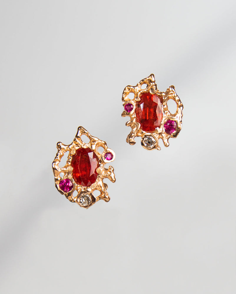 close-up of earring studs crafted from 18K Rose Gold set with Orange Sapphire, Ruby, and Diamond