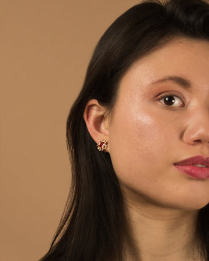 close-up of model wearing 18K rose gold stud earrings, featuring orange sapphire, ruby and diamond 