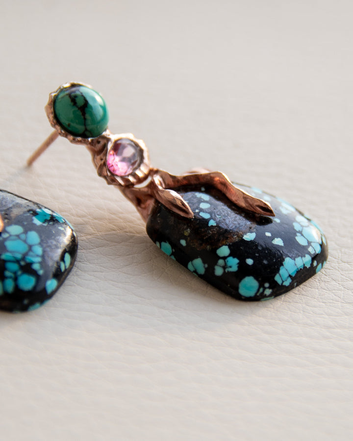 angled view of an earring with a free-form gold-plated silver setting, emphasising its sculpted design and the vibrancy of the turquoise accented with pink tourmaline