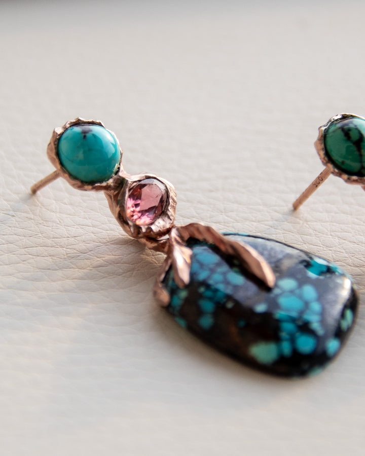 close-up of an earring, highlighting turuqoise and pink tourmaline framed by a molten gold-plated silver setting