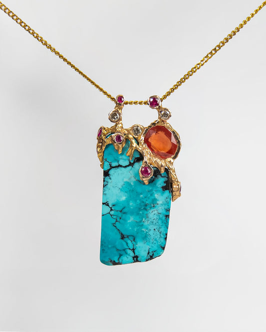 front side of a pendant featuring turquoise, orange sapphire, ruby and diamond framed by an abstract, free-form 18K gold setting