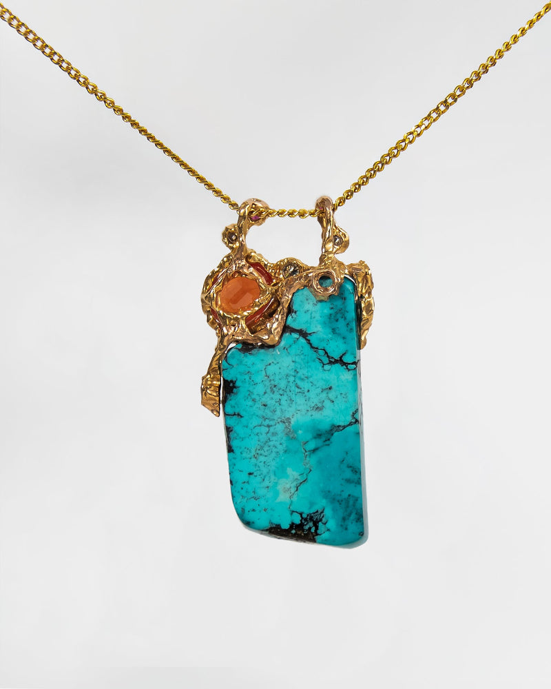 back view of a pendant showcasing the sculpted 18k gold setting , decorating the turquoise and orange sapphire